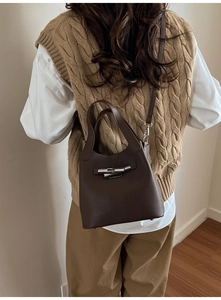 Détail d'un sac seau en cuir grainé marron foncé avec boucle en métal sur un modèle