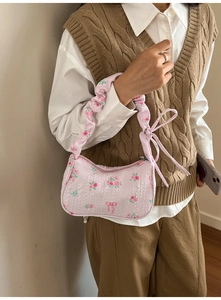 Detailed shot of pink floral shoulder bag with ruched strap and flowing ribbon accents