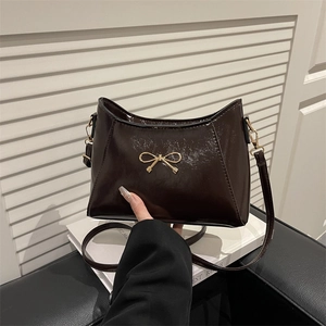 Chic dark brown faux leather shoulder bag with glossy finish and golden bow detail