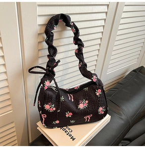 Close-up of black floral shoulder bag with pink roses and ruffled bubble fabric texture