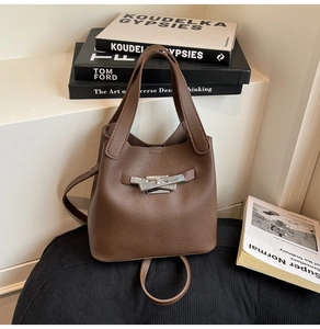Detailed view of dark brown pebbled leather texture and silver metal toggle on bucket bag