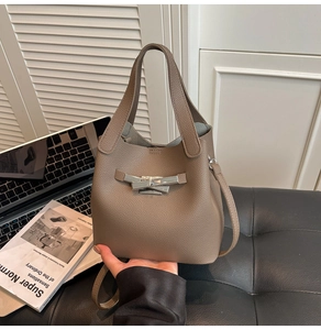 Detail of taupe leather bucket bag with silver butterfly buckle in a stylish office setting