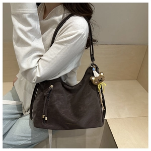 Macro detail of dark brown leather tote with vertical zipper and cute bear charm