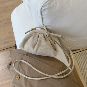 Gros plan d'un sac nuage beige plissé sur un coussin blanc avec un livre élégant