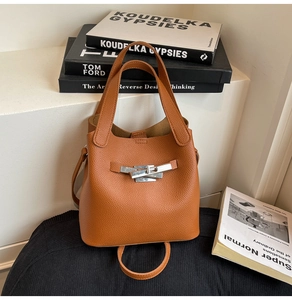 Detail of tan pebble leather bucket bag with silver twist lock and minimalist design