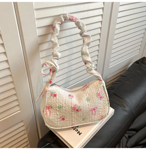 Detail of the pink floral and bow pattern on the textured pleated fabric underarm bag