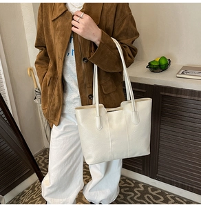 Close-up of off-white tote bag featuring wrinkled faux leather texture and shoulder straps