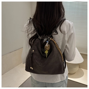 Detailed view of deep brown faux leather tote bag with cute bear pendant and hanging charms