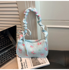 Floral pleated handbag with pink roses on book backdrop for an elegant lifestyle look