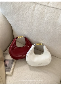 Detail of glossy crescent bags in burgundy and white with elegant gold metal buckles