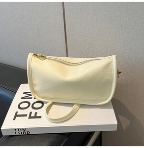 Detail of cream pleated faux leather tote bag showing gold hardware and textured finish