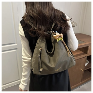Olive green suede tote bag with cute bear pendant and side zipper shown on model