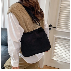 Detail of black corduroy tote bag featuring large outer pocket and textured fabric finish