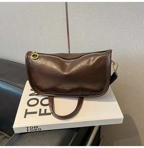 Detail view of coffee leather crossbody bag with FASHION & BAG embossing and gold rings