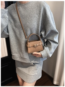 Detailed view of brown litchi pattern bag with a golden rotating metal buckle and top handle