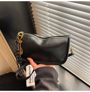 Close-up of black leather crescent tote bag with golden zipper and key pendant