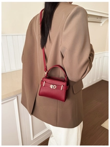 Close-up of red lychee grain leather crossbody bag with metal buckle on model