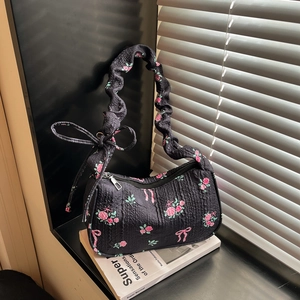 Floral black shoulder bag with pleat texture and pink rose pattern in soft natural light