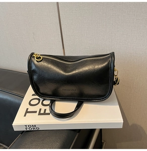 Close-up of black retro tote bag with golden hardware on a white decorative book