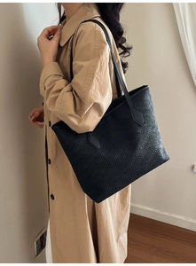 Close-up of black tote bag with embossed woven texture and long straps for daily commute