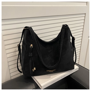 Detailed view of large black suede tote bag with golden hardware and tassel zipper accents