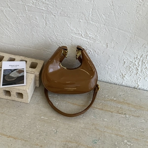 Glossy brown crescent shoulder bag with gold hardware and minimalist crescent design