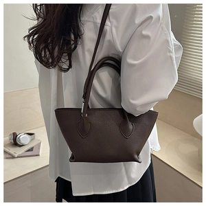 Detail view of a brown pebbled leather bucket bag styled with an elegant casual outfit