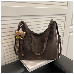 Detailed view of the dark brown suede tote bag with a cute bear keychain and fashion logo