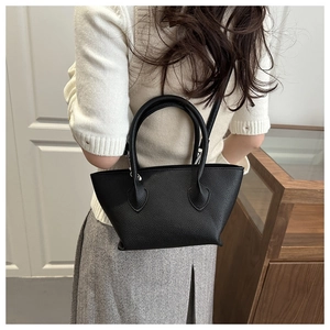 Detail of a black pebbled leather bucket bag featuring a sturdy round top handle