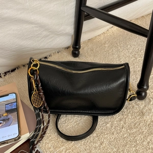 Modern black crescent crossbody bag with golden zipper and tennis racket pendant
