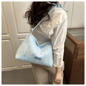 Side view of light blue embroidered tote bag with geometric texture on a female model