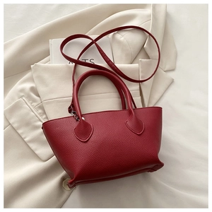 Detail of red lychee grain leather tote bag leaning against a beige blazer