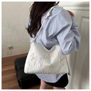 Close-up of white tote bag with colorful wave embroidery and Fashion label on the side