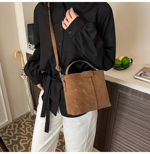 Brown vintage suede bucket bag held by a model in a stylish lifestyle setting