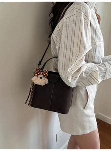 Detail of dark brown vintage bucket bag featuring a cute plush puppy charm accessory
