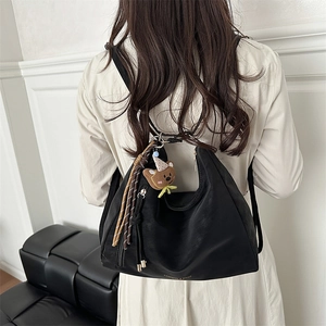 Retro black suede hobo shoulder bag with a bear pendant and woven tassel detail