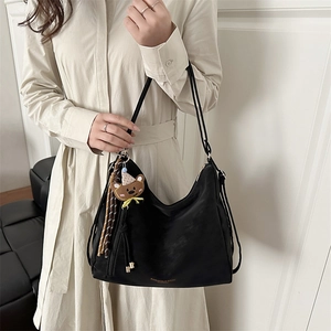 Minimalist black suede hobo tote bag with bear charm pendant and gold lettering logo