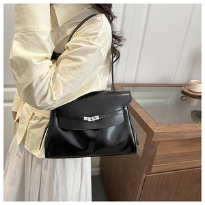 Close-up of the silver metal turn-lock and leather strap on a black luxury tote bag