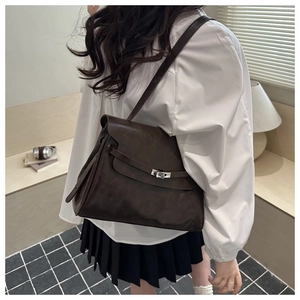 Detail of dark brown vintage crossbody bag featuring silver turn-lock and leather straps