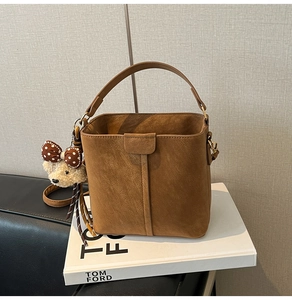 Detail of brown suede bucket bag featuring a cute bear pendant on Tom Ford book