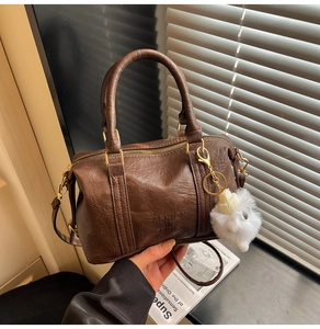 Detail of vintage brown bowling bag featuring embossed text and soft plush ball charm