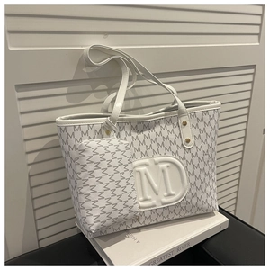 Dettaglio set borsa tote trendy con stampa monogramma M e pochette abbinata su libri