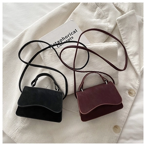 Detail view of retro suede square bags in black and burgundy with wavy flap edges