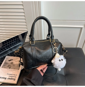 Detail of black pebbled leather Boston bag with embossed logo and fuzzy monster charm