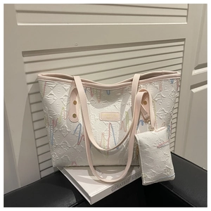 Close-up of white tote bag with colorful embroidery and matching mini pouch detail