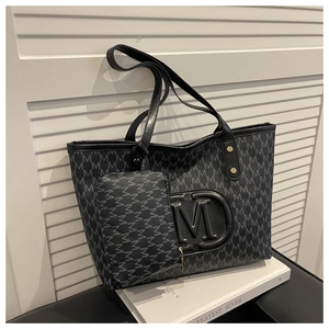 Dettaglio della borsa tote nera con monogramma, logo a rilievo e mini pochette
