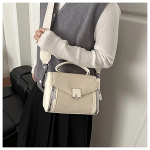 Detail of cream white crossbody bag featuring silver hardware and a wide fashion strap