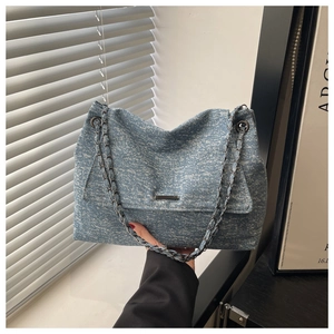 Detail der blauen Denim-Tasche mit Schneeflocken-Textur und eleganter schwarzer Metallkette