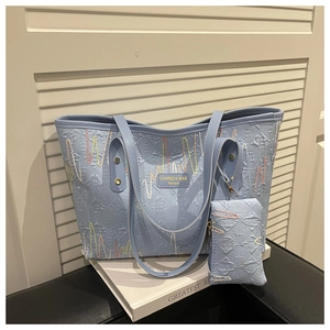 Detail of light blue textured tote bag with colorful stitching and mini pouch