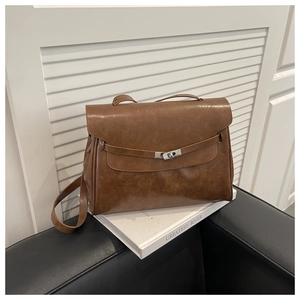 Detail of vintage brown textured leather tote bag featuring a silver twist-lock and top handle
